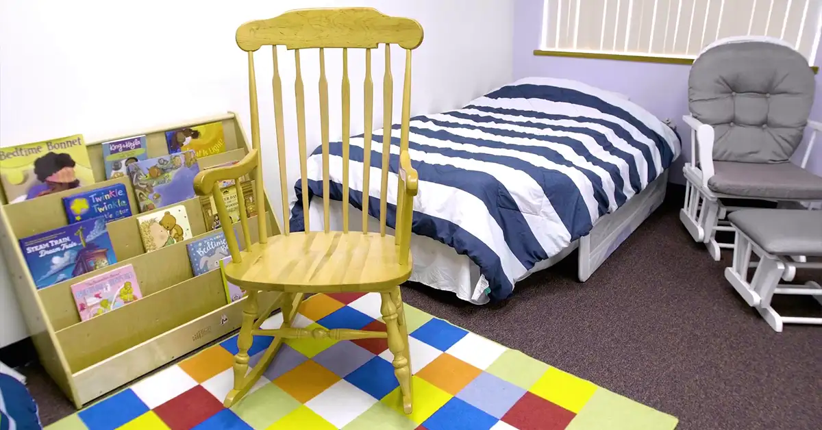 A bedroom with rocking chair used for overnight and evening emergency childcare visits at Jeremiah's Place