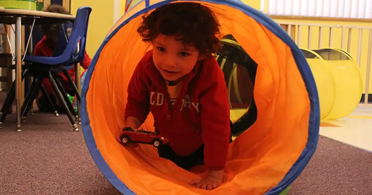 A young child crawls through a play tunnel at Jeremiah's Place